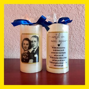 May include: Two white pillar candles with gold trim. One candle has a photo of an older couple and the other has the text "until we meet again" with a heart symbol. The text continues with a poem about remembering loved ones.
