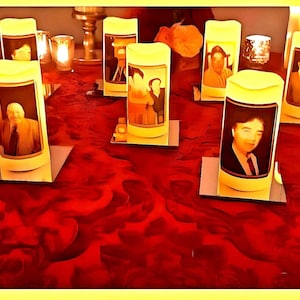 May include: A red table with several yellow candles with portraits of people on them. The candles are on small square mirrors.
