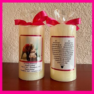 May include: Two white pillar candles with pink ribbons and a personalized message on each. The left candle has a photo of an older couple. The right candle has a message that reads "At Heaven and I watch if you know with signs that when you're laughing and the days around you to calm you as you weep. I see signs so you know you're not alone. Don't feel guilty because you have a life that was denied to me. So be your life laugh again, enjoy yourself and be free then I know with every breath you take you'll be taking one for me."