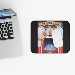 May include: A black mouse pad with a colorful image of a Nutcracker soldier. The Nutcracker is holding a sword and has a red and white uniform. The text "George Balanchine's The Nutcracker" is printed above the image.