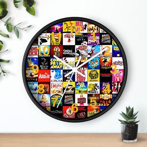 May include: A black round wall clock with a white face and gold numbers. The clock face is covered with colourful images of Broadway show posters.