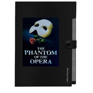 May include: Black file folder with a white mask and red rose graphic. The text "THE PHANTOM OF THE OPERA" is printed on the folder. The folder has a button closure and a label that says "Make things happen."