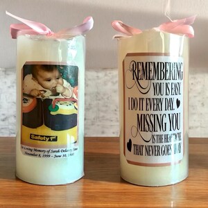 May include: Two white memorial candles with personalized labels. One candle features a photo of a baby and the text "In Loving Memory of Sarah Delaney Sins November 8, 1999 - June 10, 2000". The other candle has the text "Remembering you is easy. I do it every day. Missing you is the heartache that never goes away."