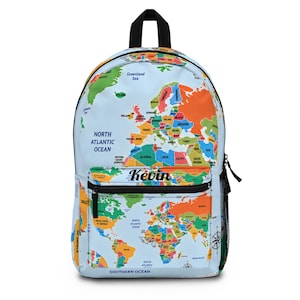 May include: A light blue backpack featuring a colourful world map print with various countries and oceans labelled. The front pocket displays the name Kevin in black script text. The bag includes a black top handle, black zips, and side mesh pockets.