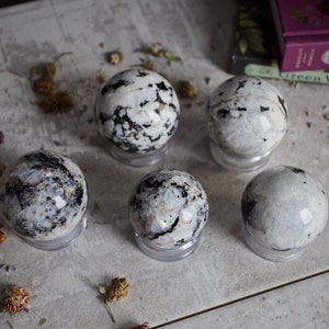 May include: Five white and black gemstone spheres on clear stands. The spheres are iridescent and have a speckled pattern.