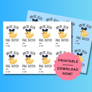 May include: A sheet of printable gift tags featuring a yellow rubber duck wearing black mouse ears. The text reads YOU'VE BEEN PIXIE DUSTED! FROM: IN CABIN:. A pink starburst shape with the text PRINTABLE DOWNLOAD NOW! is layered over the tags.