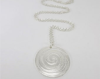 May include: A silver necklace with a round pendant featuring a textured spiral design.