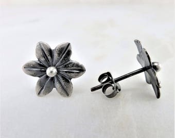 May include: A pair of silver flower stud earrings with a textured finish. The earrings have a small silver bead in the center of each flower.