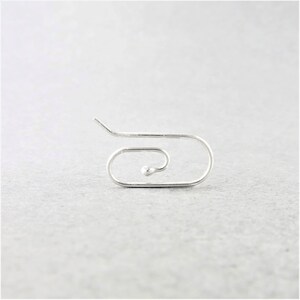 May include: A single, silver-colored earring with a unique, minimalist design. The earring features a curved, open shape with a small, round bead at the center of the spiral. The design is simple and modern, suitable for everyday wear.
