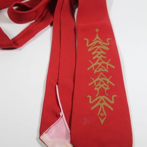 May include: A bright red necktie with a gold-colored decorative pattern. The tie is made of a smooth fabric and features a classic design. The tie is a formal accessory.
