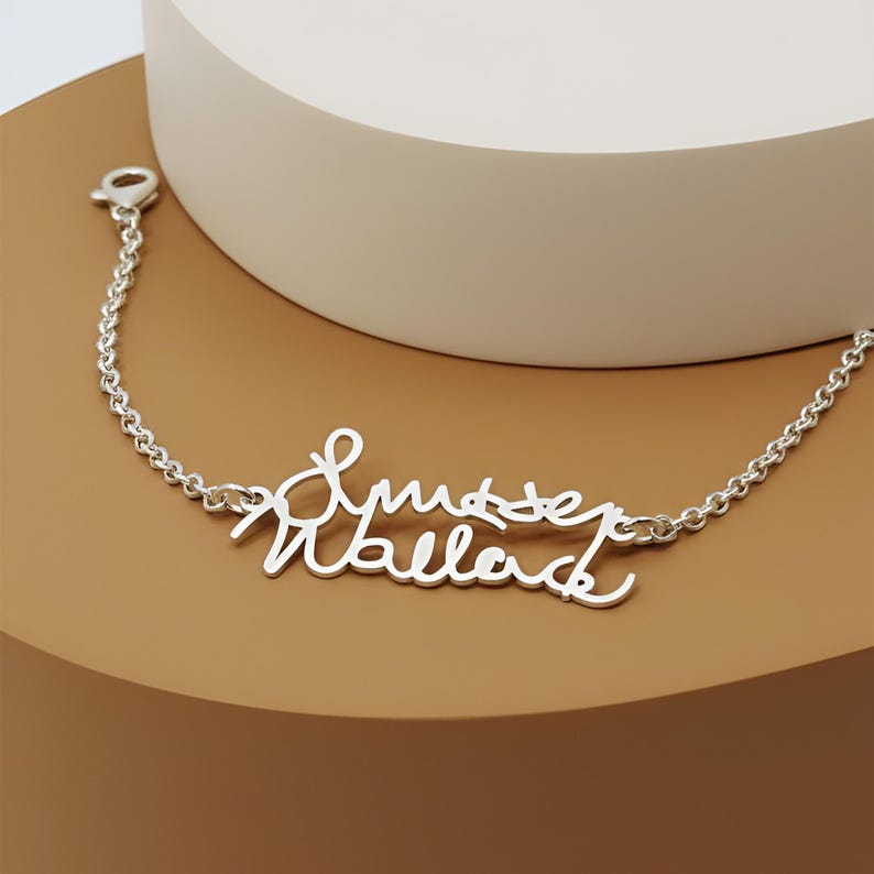 May include: A silver-toned metal bracelet featuring a central nameplate with the cursive script text "Smyser Wallace". The bracelet is constructed with a delicate chain link design and includes a small lobster claw clasp at one end of the chain.