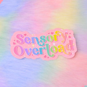 Pu&ograve; includere: Un adesivo rosa con il testo "Sensory Overload" in colori arcobaleno con accenti di glitter. L'adesivo &egrave; su uno sfondo sfocato color arcobaleno.