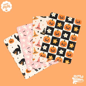 Könnte beinhalten: Vier dekorative Halloween-Matten mit verschiedenen Mustern. Designs umfassen schwarze Katzen, Kürbisse, Hexenhüte, Geister und ein Schachbrettmuster mit Kürbissen und Blumen. Die Matten sind in den Farbtönen Orange, Rosa, Schwarz und Weiß gehalten. Die Wörter "Hand Made" und "Guts & Glitter" sind sichtbar.