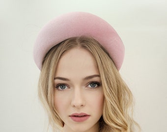 May include: A woman with long blonde hair is wearing a pink velvet headband. The headband is wide and has a rounded shape.