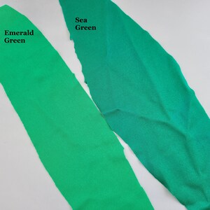 May include: Two fabric swatches, one emerald green and one sea green. The swatches are laid out side by side on a white surface.
