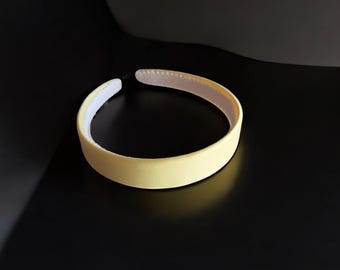 May include: A yellow headband with a white lining. The headband is made of a soft, flexible material.