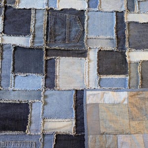 May include: A patchwork quilt made from denim fabric. The quilt is made up of squares of different sizes and colours of denim, all sewn together with a frayed edge. The quilt is a unique and handmade piece of art.