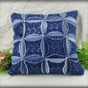 May include: A blue denim and lace pillow with a patchwork design. The pillow is made from recycled denim and features a unique, hand-stitched design.