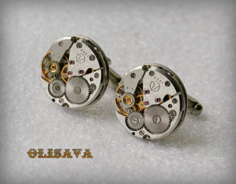 Peut inclure: Une paire de boutons de manchette argent&eacute;s avec un design circulaire mettant en valeur des engrenages de montre apparents et un centre de couleur or. Les boutons de manchette ont un fond argent&eacute; et un centre dor&eacute; avec le texte "6081" imprim&eacute; dessus.