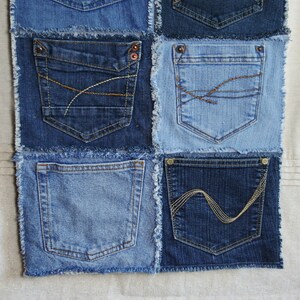 Op de afbeelding: Een patchworkdeken gemaakt van denim stof met verschillende gekleurde stiksels. De deken bestaat uit negen vierkanten, elk met een andere zak. De zakken zijn allemaal verschillend van grootte en vorm, en sommige hebben decoratieve stiksels.