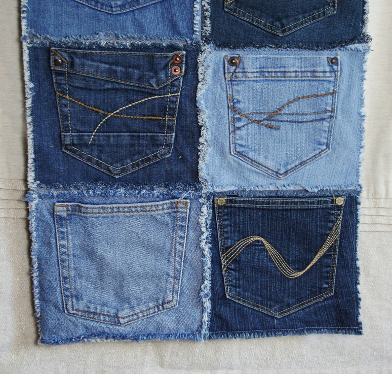 Op de afbeelding: Een patchworkdeken gemaakt van denim stof met verschillende gekleurde stiksels. De deken bestaat uit negen vierkanten, elk met een andere zak. De zakken zijn allemaal verschillend van grootte en vorm, en sommige hebben decoratieve stiksels.