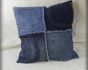May include: A blue denim pillow with different shades of blue denim sewn together in a patchwork design. The pillow has a frayed edge and features multiple pockets.