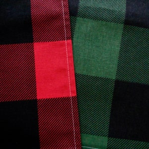 May include: Two pieces of fabric with a black, red, and green plaid pattern. The fabric on the left is red and black, and the fabric on the right is green and black.