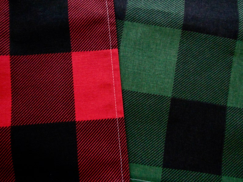 May include: Two pieces of fabric with a black, red, and green plaid pattern. The fabric on the left is red and black, and the fabric on the right is green and black.