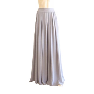 May include: A long, flowing grey skirt with pleats. The skirt is made of a soft, lightweight fabric and has a simple, elegant design.