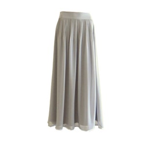 May include: A long, flowing grey skirt with pleats. The skirt is made of a lightweight fabric and has a simple, elegant design.