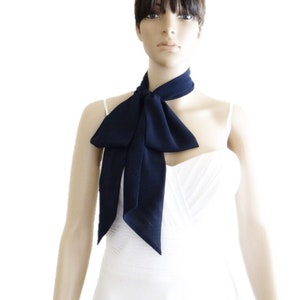 Puede incluir: Una corbata azul marino atada con un lazo está drapeada alrededor del cuello de un maniquí. El lazo está centrado en el pecho, con los extremos largos de la corbata colgando. El maniquí lleva una camiseta blanca.