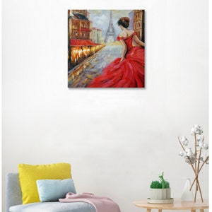 May include: Oil painting of a woman in a red dress walking down a cobblestone street in Paris. The Eiffel Tower is visible in the background. Buildings with red awnings line the street.