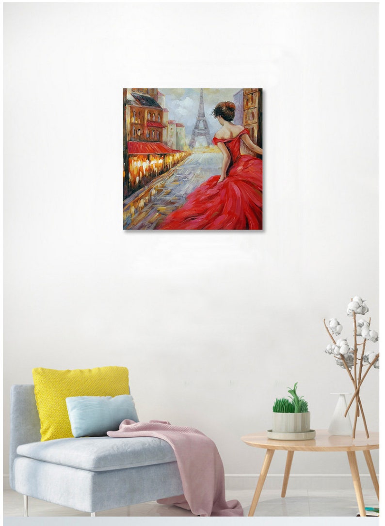 May include: Oil painting of a woman in a red dress walking down a cobblestone street in Paris. The Eiffel Tower is visible in the background. Buildings with red awnings line the street.