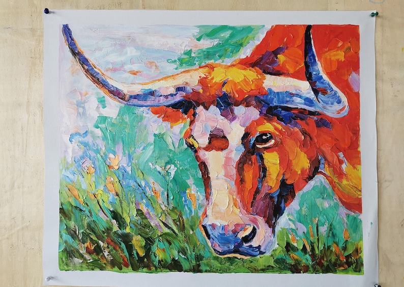 May include: An oil painting of a longhorn steer's head, rendered in vibrant, textured brushstrokes. The artwork features a palette of warm colors, including orange, red, and yellow, contrasted with cool blues and greens. The steer's face is white, and the horns are blue.