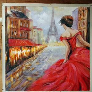 May include: Oil painting of a woman in a red dress walking down a Parisian street. The Eiffel Tower is visible in the background. Buildings with red awnings line the street. The artwork is on a white canvas.
