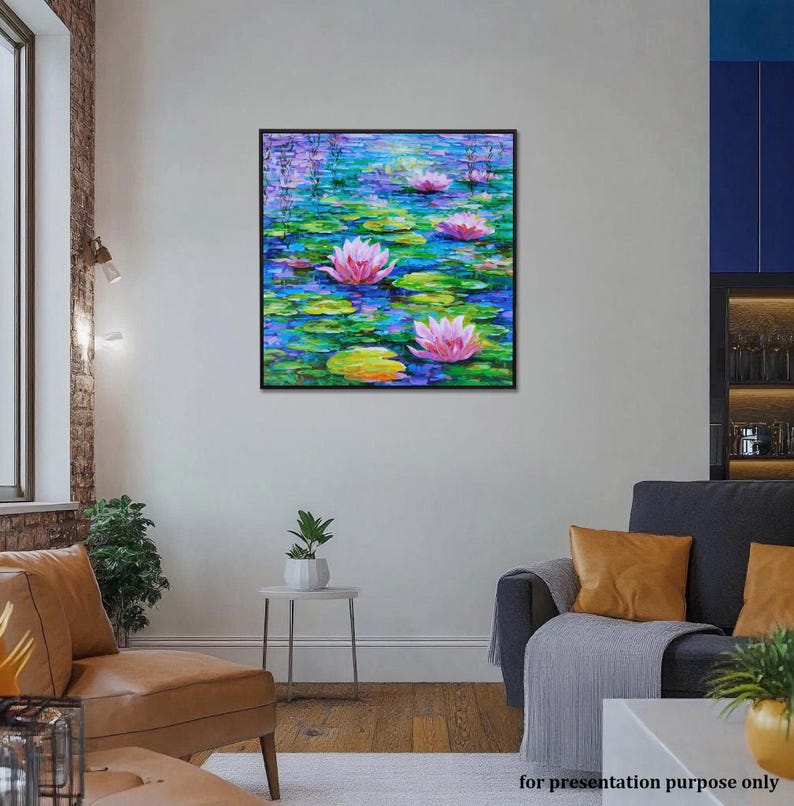 May include: A framed painting depicting a pond scene with pink water lilies and green lily pads. The water is a mix of blues and greens, with purple accents. The artwork is displayed in a living room setting.