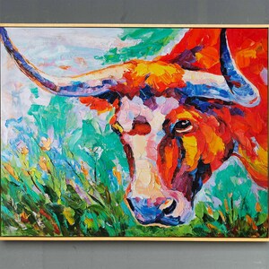 May include: A vibrant oil painting of a longhorn steer's head, framed in gold. The artwork features bold brushstrokes in shades of red, orange, blue, and green, creating a textured and expressive piece of art.