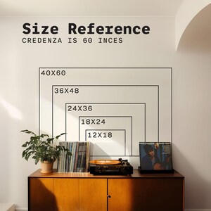 May include: A wall graphic displaying size reference rectangles labeled 12x18, 18x24, 24x36, 36x48, and 40x60 inches above a wooden credenza. The text reads Size Reference and Credenza is 60 inces. A record player, vinyl records, and a plant sit on top.