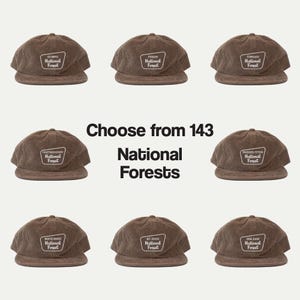 May include: Nine brown corduroy baseball caps arranged in a grid, each featuring a unique embroidered patch with the text National Forest. The central text reads Choose from 143 National Forests, highlighting the variety of available options.