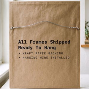 May include: A rectangular picture frame backing made of brown kraft paper. The text reads: All Frames Shipped Ready To Hang, KRAFT PAPER BACKING, HANGING WIRE INSTALLED. A silver metal hanging wire is attached to the top section of the frame.