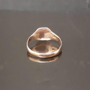 May include: A gold signet ring with a smooth, rounded top. The ring is made of a shiny metal and has a simple design.