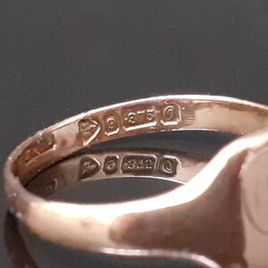 May include: Close-up of the inside of a gold signet ring with the inscription "9 375" on the band.
