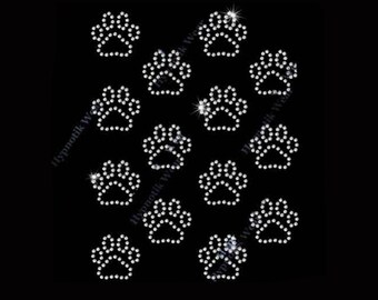 May include: A collection of sparkling, rhinestone paw prints arranged on a black background. Each paw print is composed of numerous small, clear rhinestones, creating a shimmering effect. The design is suitable for pet-themed crafts.