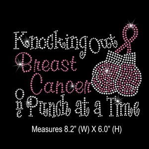 May include: Black graphic with the text "Knocking Out Breast Cancer, Punch at a Time" in white and pink rhinestones. The design includes pink boxing gloves with a pink ribbon, measuring 8.2" wide and 6.0" high.