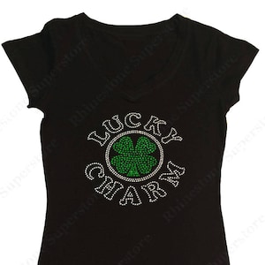 Puede incluir: Camiseta negra con un dise&ntilde;o de pedrer&iacute;a que dice "Lucky Charm" con un tr&eacute;bol de cuatro hojas verde en el centro.