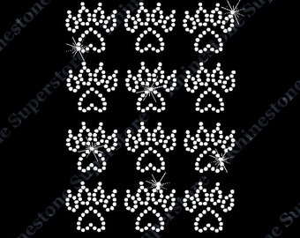 May include: A set of twelve white rhinestone paw prints. The paw prints are arranged in four rows of three.