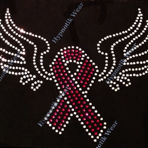 May include: Pink and white rhinestone design of a ribbon with wings. The ribbon is a symbol of support and awareness.