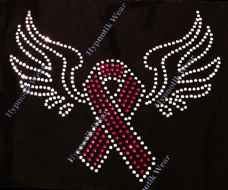 May include: Pink and white rhinestone design of a ribbon with wings. The ribbon is a symbol of support and awareness.