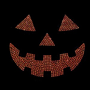 May include: Orange and yellow jack-o'-lantern face made of rhinestones on a black background.