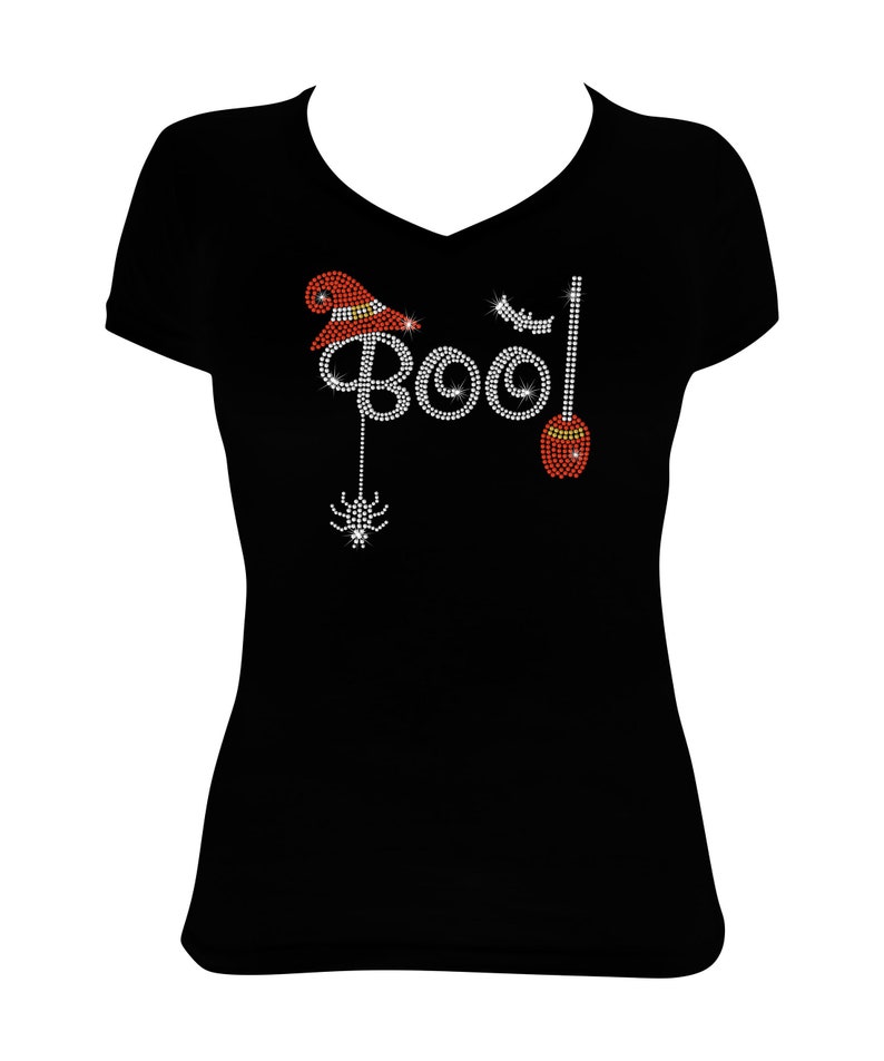Peut inclure: T-shirt noir avec un motif en strass qui dit "Boo!" avec un chapeau de sorci&egrave;re, un balai et une araign&eacute;e.
